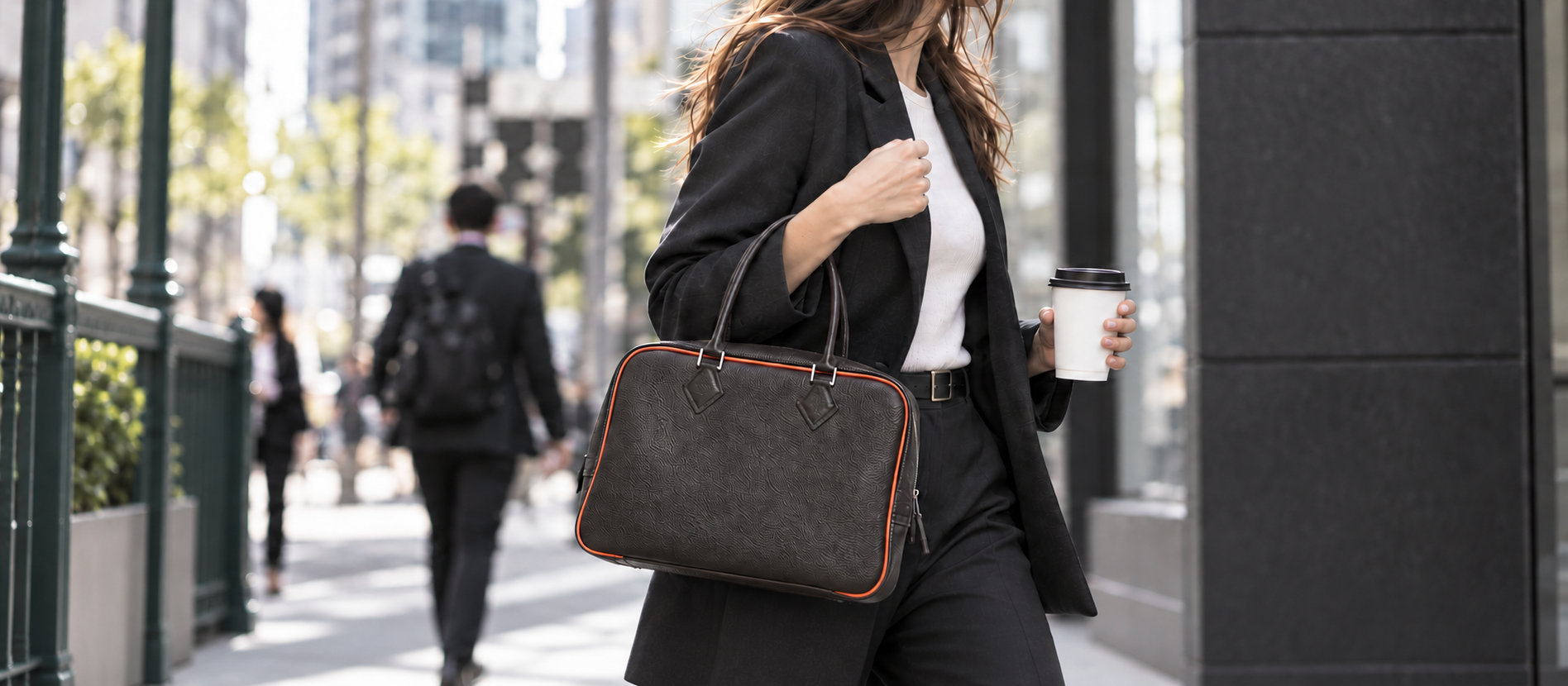 Commuter carrying the LAVA FRAME 02 espresso handbag with orange piping